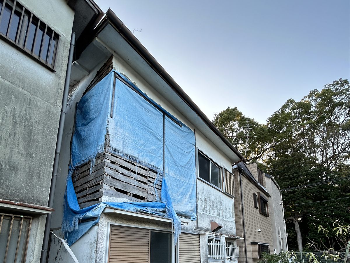 雨漏りの応急処置としてブルーシートがかけられたままの空き家の外観。傷みが進んだ築古住宅