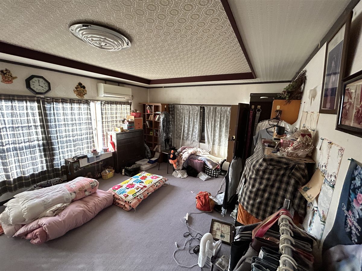 家具・布団・衣類が残されたままの空き家の室内。残置物がそのままの状態