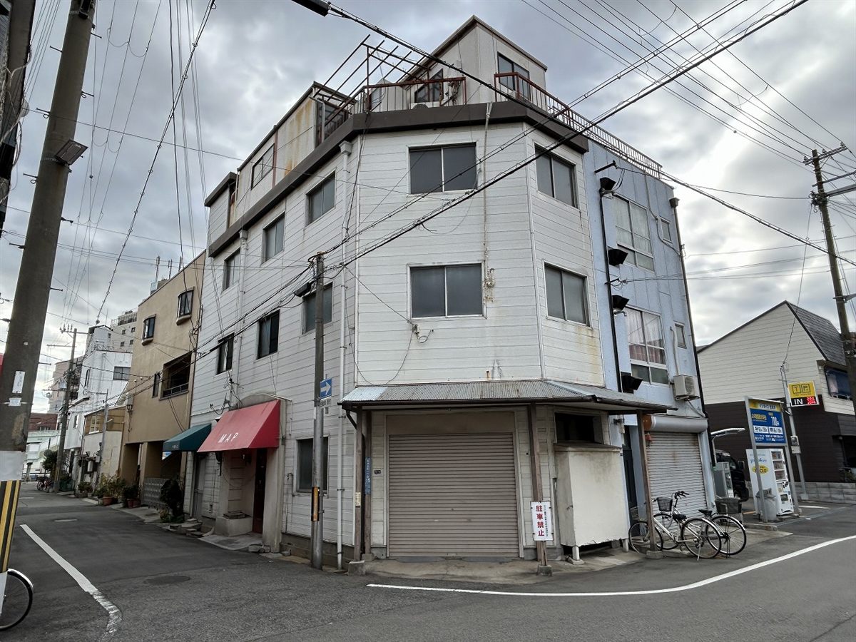 改修前のイノベース杭瀬の外観。色あせた外壁と、1階に並ぶ店舗シャッター。兵庫県尼崎市杭瀬本町